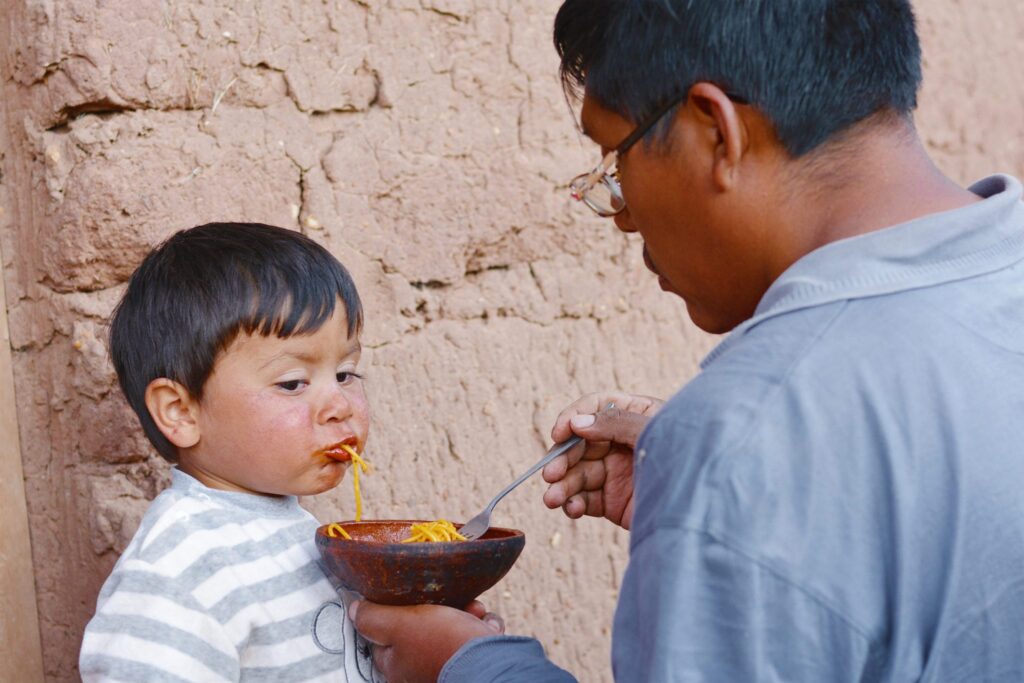 Native american man feeding his little son in the countryside.