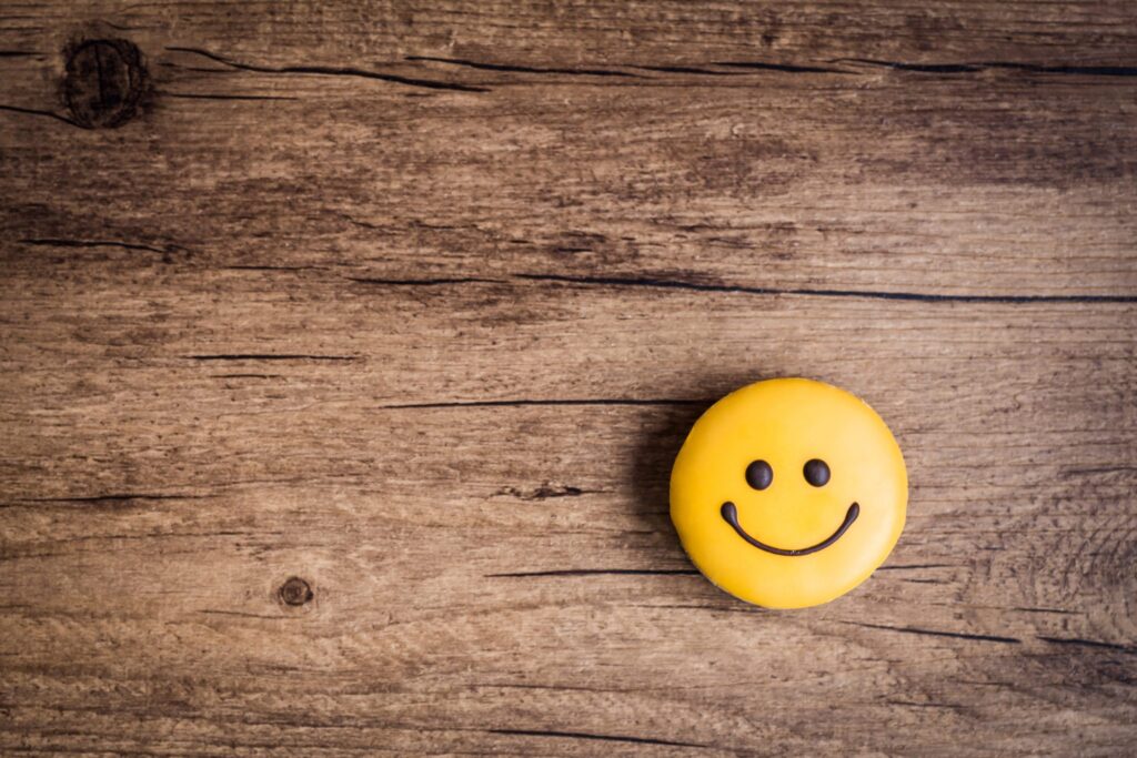 Glazed cookies in the shape of a smiley on a wooden background